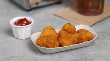 5 popcorn chickens in paper bowl with cup of ketchup