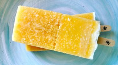 Two orange popsicles stacked on a blue plate