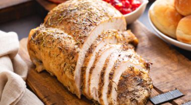 Half cut up turkey breast roast on wood cutting board