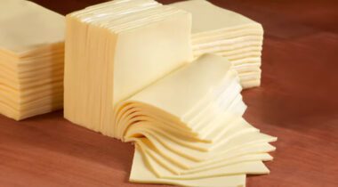 slices of white american cheese on white cutting board.