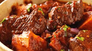 bowl of beef stew with big chunks of beef, sweet potato and spices