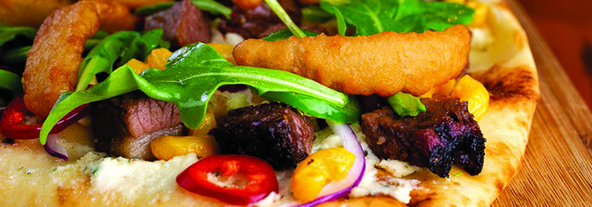 flatbread with bbq brisket, onion, peppers, arugula, goat cheese on wood platter