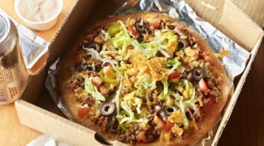 taco pizza with hormel beef crumble, lettuce, tortilla chips, tomatoes and black olives