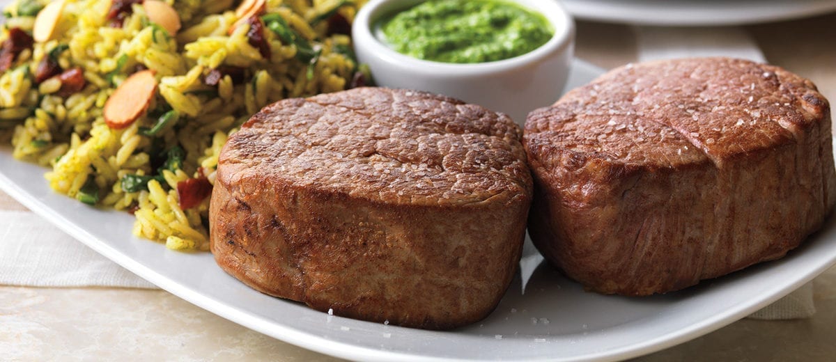 cooked beef tenderloins with rice and pesto sauce in ramekin