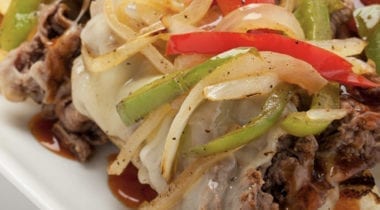 steak topped with peppers and onions