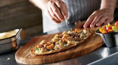 person making chicken flatbread pizza