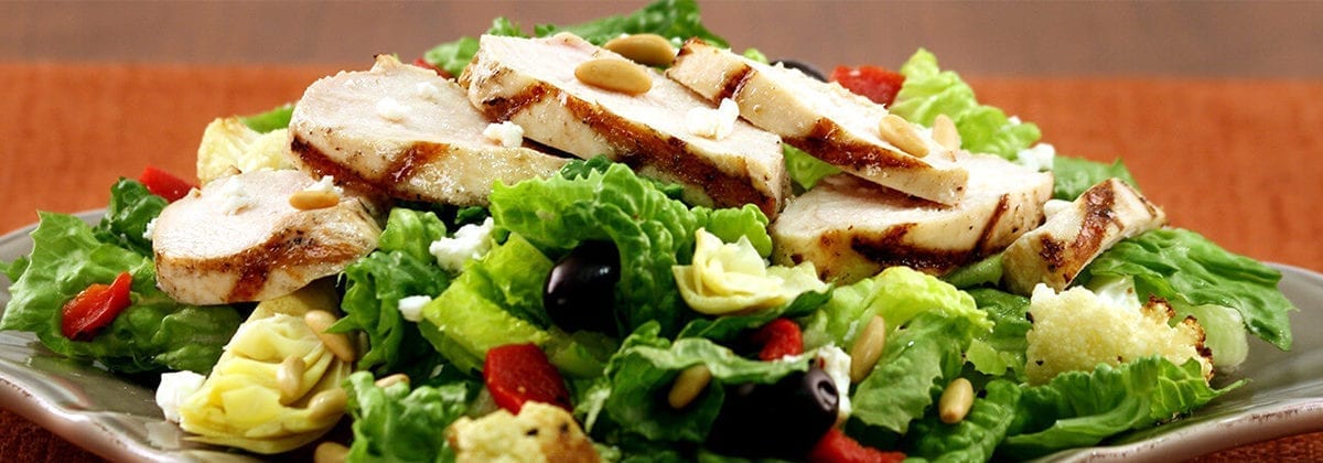 sliced grilled chicken on mediterranean salad