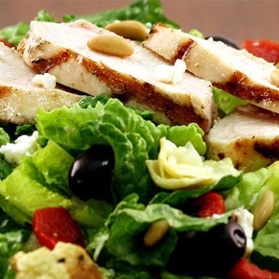 sliced grilled chicken on mediterranean salad