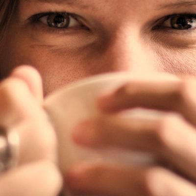 woman sipping mug, smiling with eyes