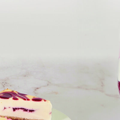 raspberry trifle dessert in wine glass next to plate with slice of raspberry cheesecake and another wine glass with close up of raspberry cheesecake trifle.