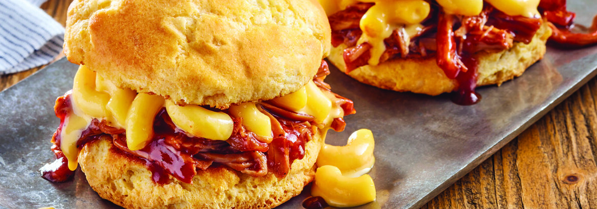 two pulled pork Mac n' cheese sandwiches on biscuits, plated on metal plate