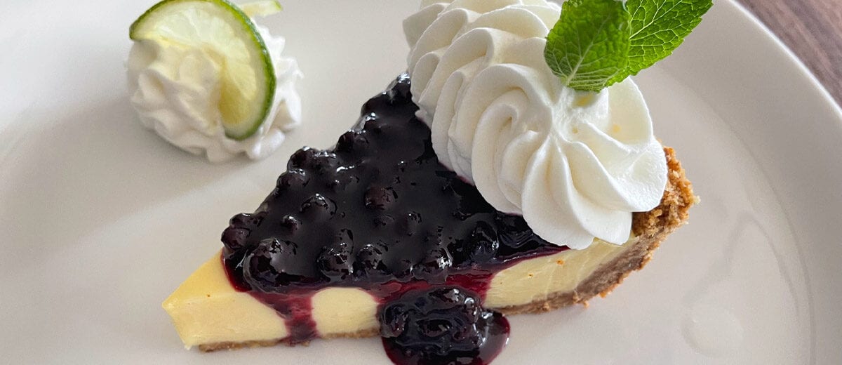 lemon lime pie slice with blueberry sauce and whip cream