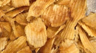 fresh fried crinkle chips on a black plate with dipping sauce