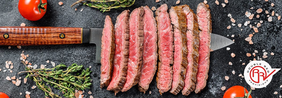 sliced flat iron steak on top of rustic knife on kitchen counter