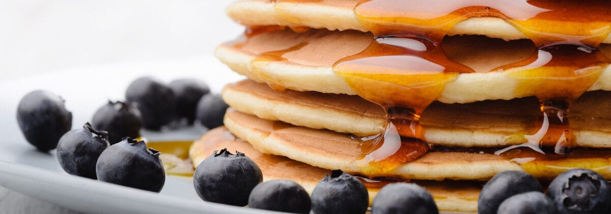 pancakes and syrup surrounded by blueberries