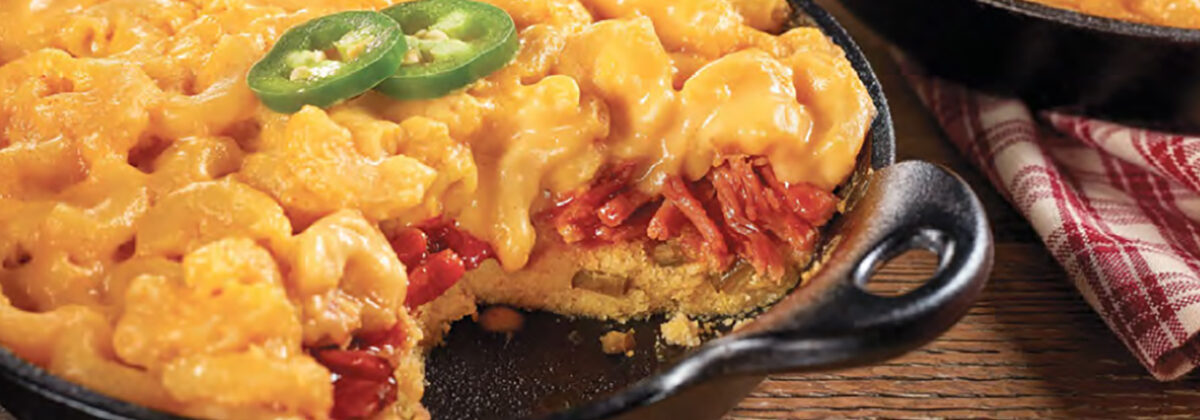 Stuffed Mac-n-cheese tart in cast iron skillet on wooden table