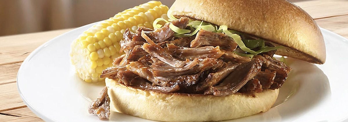 pulled pork on a bun with corn on the cob