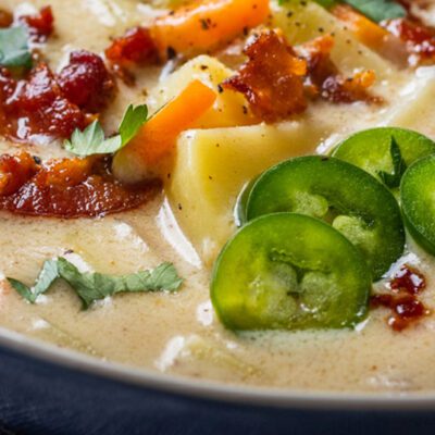 Creamy soup with bacon potatoes cheese jalapeños in a blue bowl on table