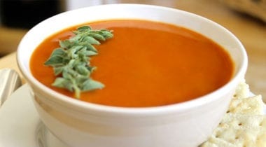 tomato soup in a white bowl with garnish